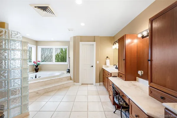 a spacious bathroom with a granite countertop sink a mirror and a bathtub