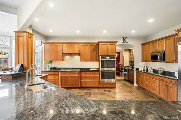 a large kitchen with granite countertop a large counter top stainless steel appliances and cabinets