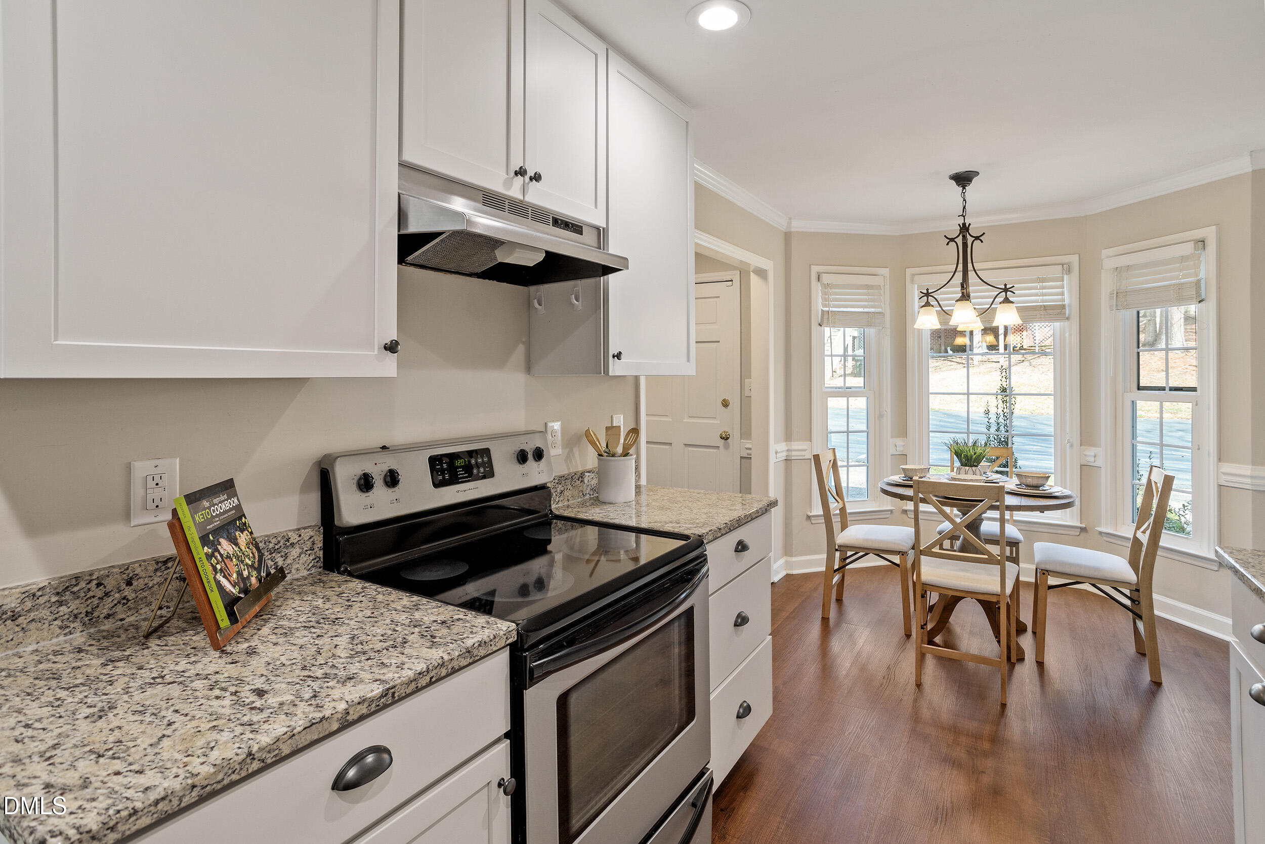 4619 Hershey Court Raleigh, NC 27613 - Photo 12 of 43 a kitchen with granite countertop stainless steel appliances a stove a sink a dining table and chairs with wooden floor