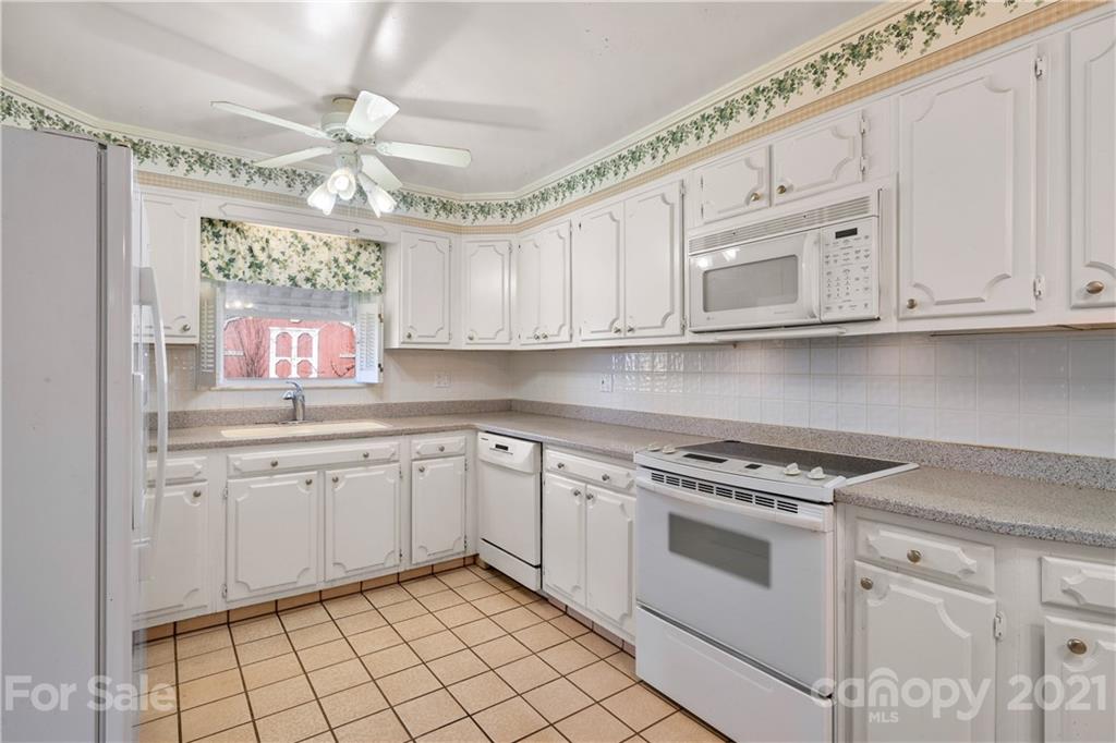 85 Walnut Ford Road Clyde, NC 28721 - Photo 15 of 24 a kitchen with granite countertop white cabinets stainless steel appliances and a window