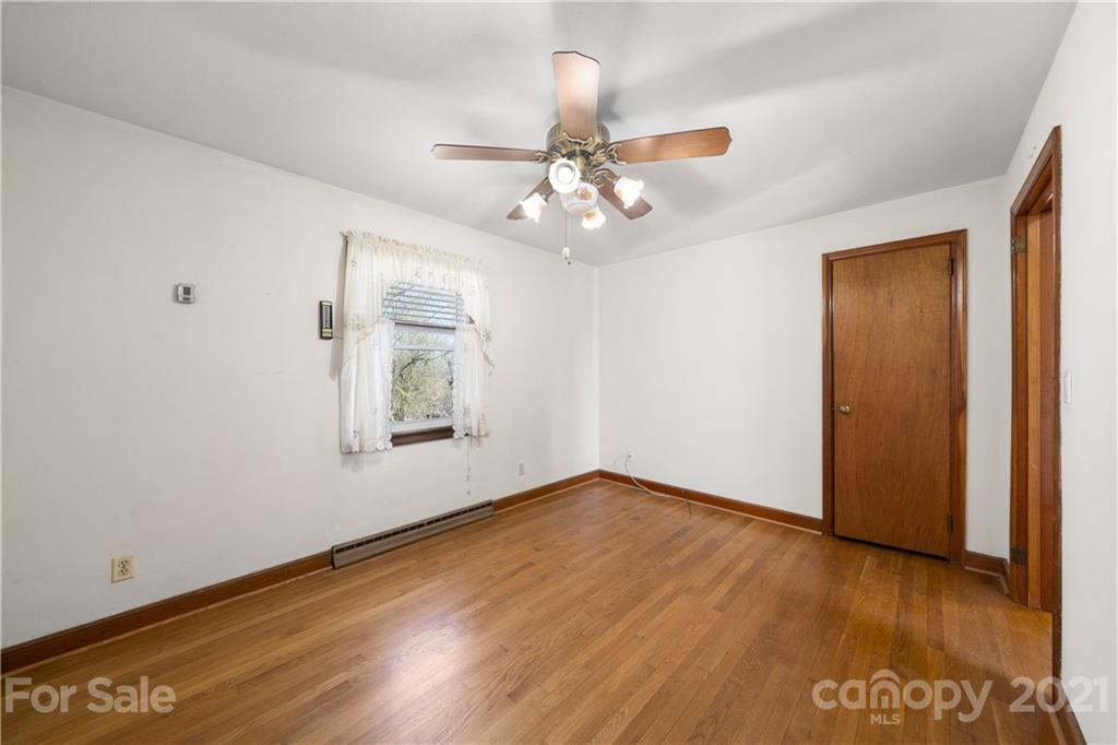 85 Walnut Ford Road Clyde, NC 28721 - Photo 17 of 24 an empty room with wooden floor chandelier fan and windows