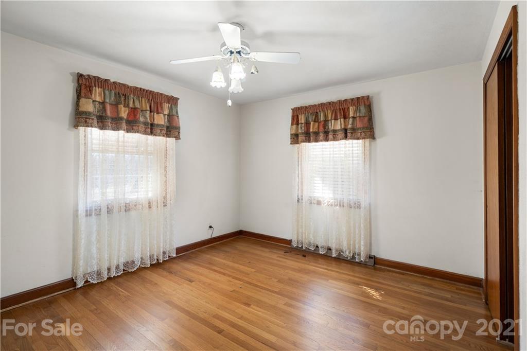 85 Walnut Ford Road Clyde, NC 28721 - Photo 19 of 24 an empty room with wooden floor chandelier fan and windows