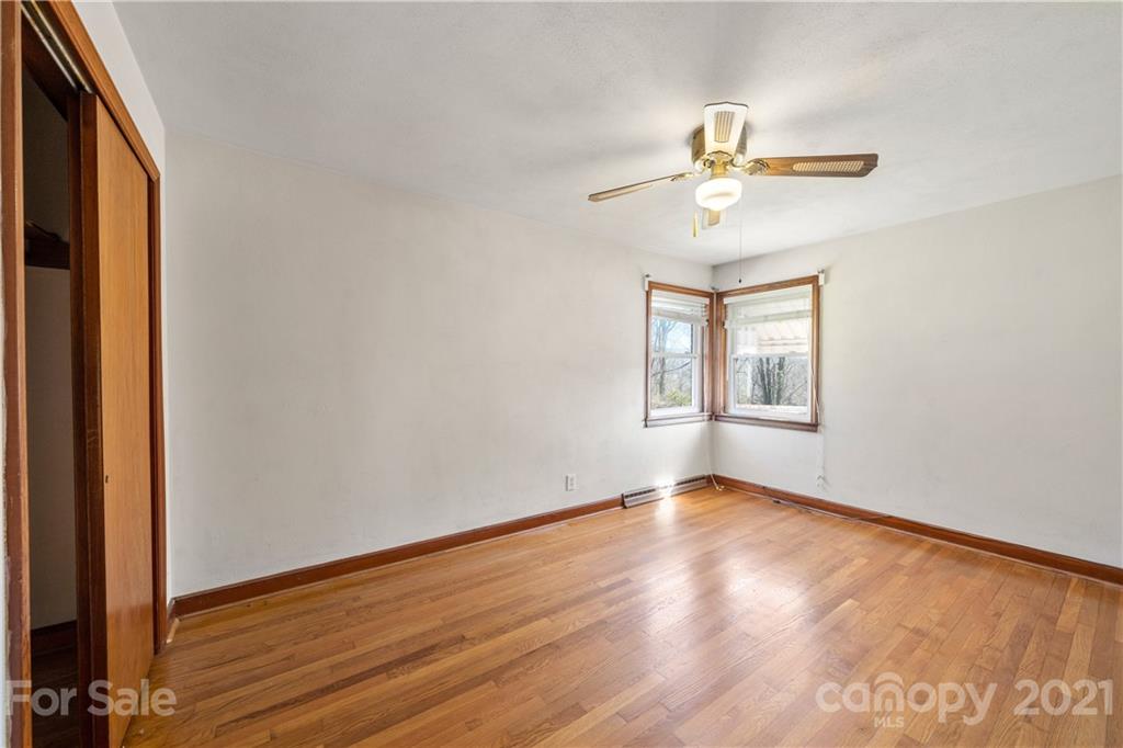 85 Walnut Ford Road Clyde, NC 28721 - Photo 20 of 24 an empty room with wooden floor fan and windows