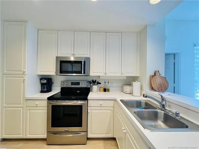 a living room with stainless steel appliances furniture a couch and a kitchen view