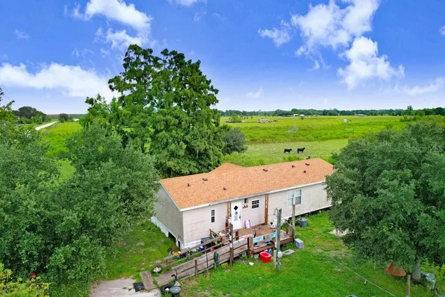 an aerial view of a house with garden space and trees all around
