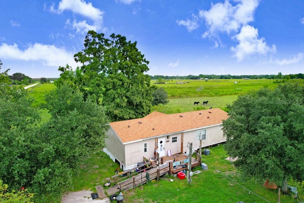 an aerial view of a house with garden space and trees all around