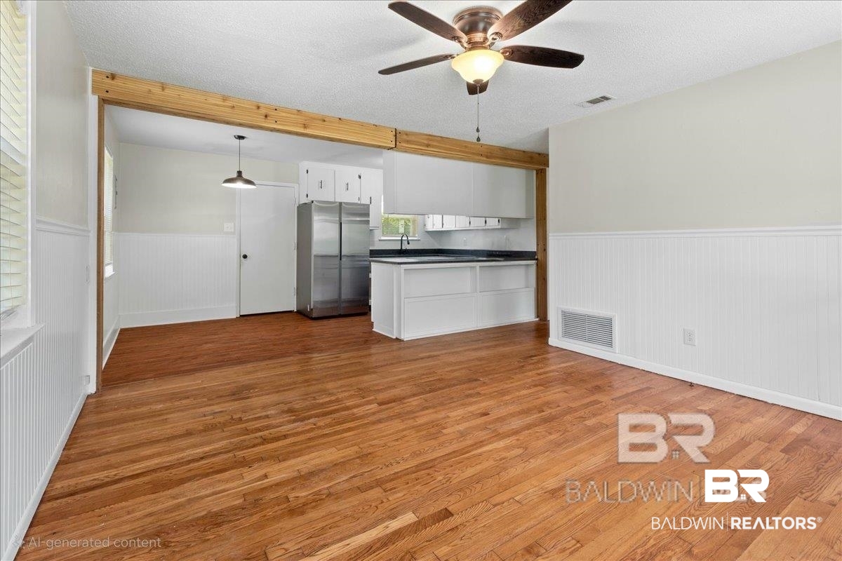 29397 Loper Road Loxley, AL 36551 - Photo 8 of 22 Kitchen featuring a peninsula, a wainscoted wall, white cabinets, dark countertops, and freestanding refrigerator