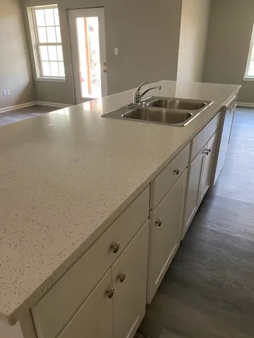 a view of a kitchen with granite countertop a sink and dishwasher with wooden floor