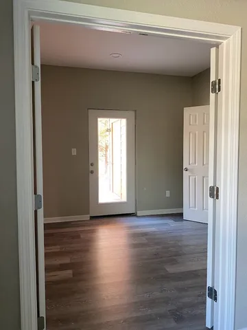 a view of an empty room with wooden floor and a window