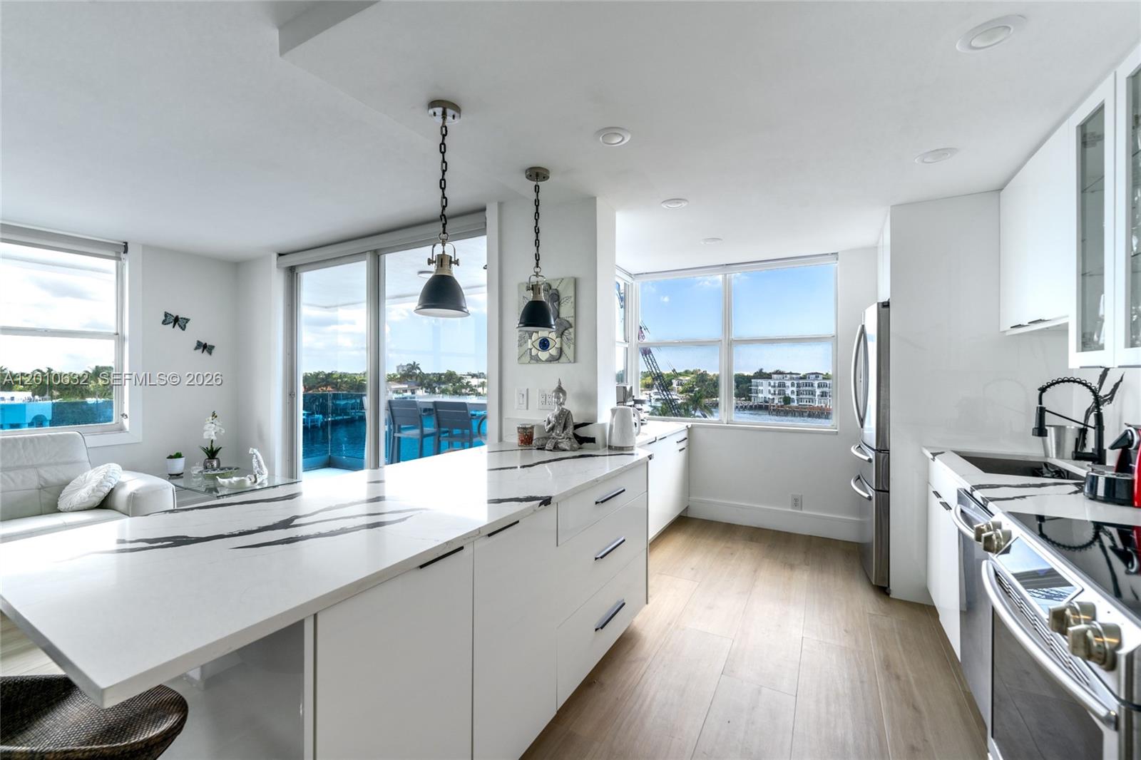 2639 North Riverside Drive, Unit 501 Pompano Beach, FL 33062 - Photo 7 of 39 a large white kitchen with a large window a sink stainless steel appliances and cabinets