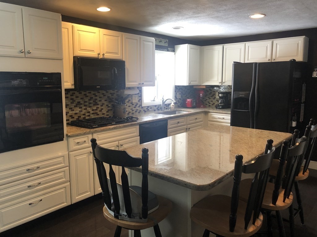 74 Old Stage Road Chelmsford, MA 01824 - Photo 7 of 33 a kitchen with a table chairs refrigerator and microwave