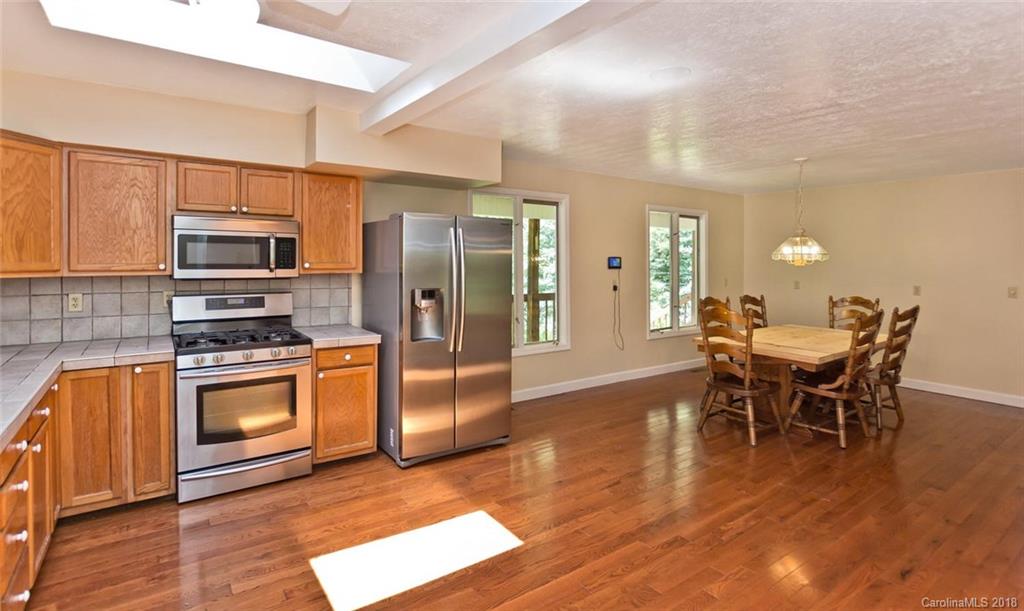 282 Fox Creek Road Mars Hill, NC 28754 - Photo 4 of 36 a kitchen with stainless steel appliances granite countertop a stove a refrigerator a sink a dining table and chairs with wooden floor