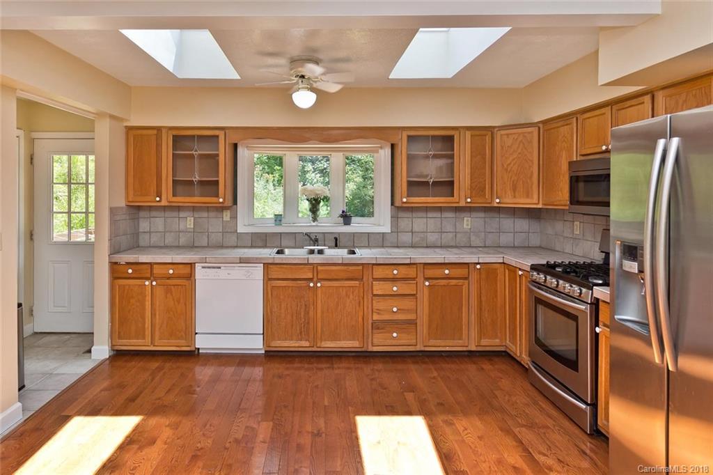 282 Fox Creek Road Mars Hill, NC 28754 - Photo 5 of 36 a kitchen with stainless steel appliances granite countertop wooden cabinets a stove a sink and dishwasher with wooden floor