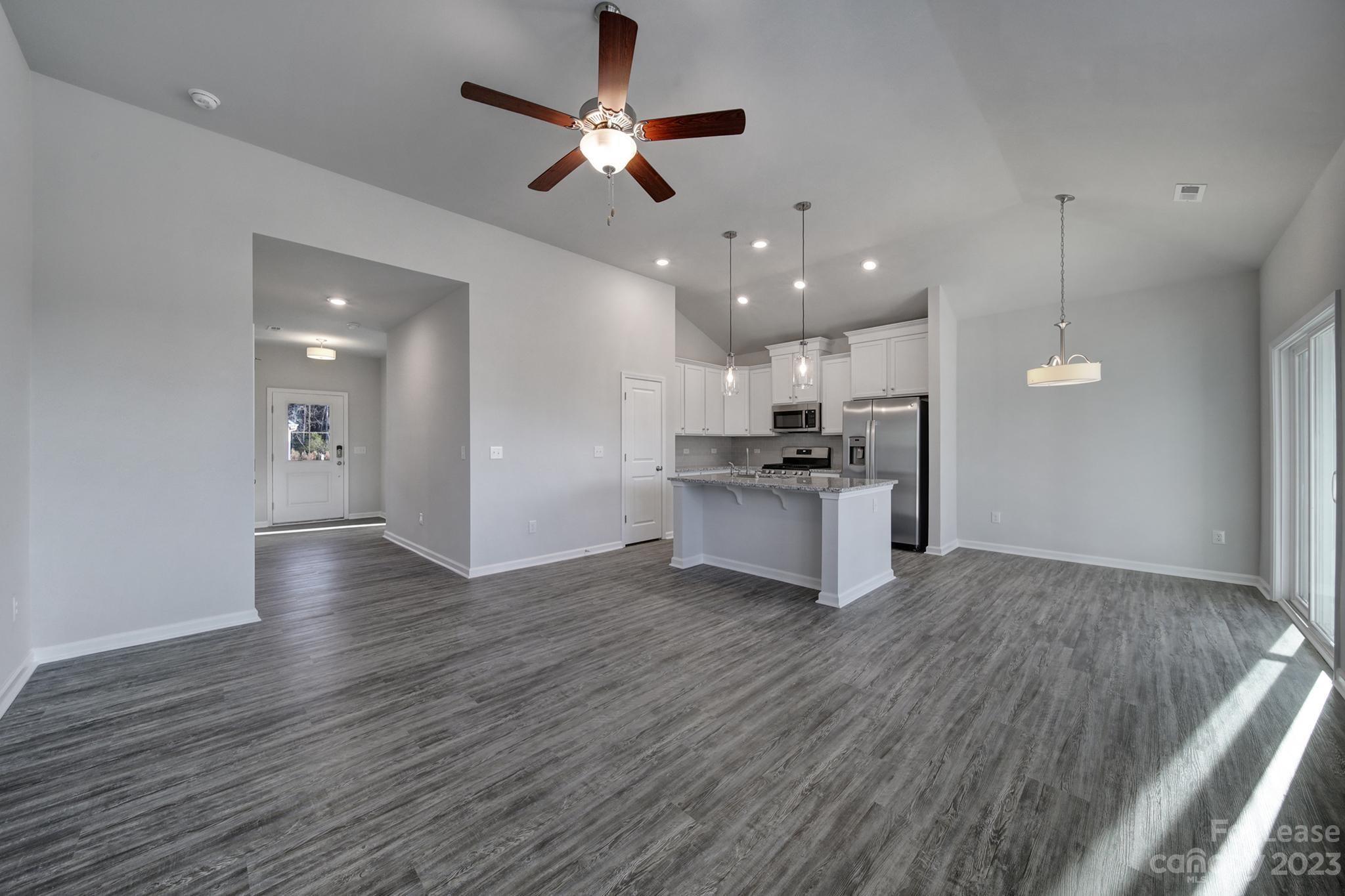 8201 Mccormick Street Terrell, NC 28682 - Photo 10 of 28 a view of an empty room and kitchen with ceiling fan wooden floor