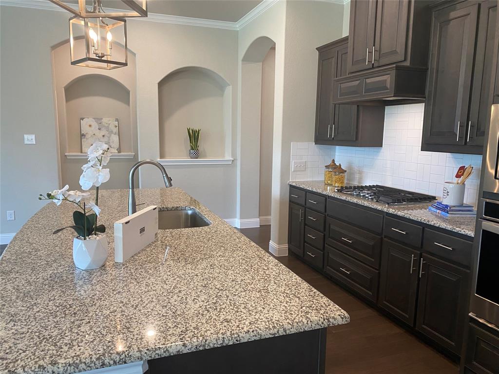 209 Johnson Street Granbury, TX 76048 - Photo 12 of 40 Kitchen featuring dark hardwood / wood-style flooring, tasteful backsplash, a kitchen island with sink, and stainless steel gas stovetop