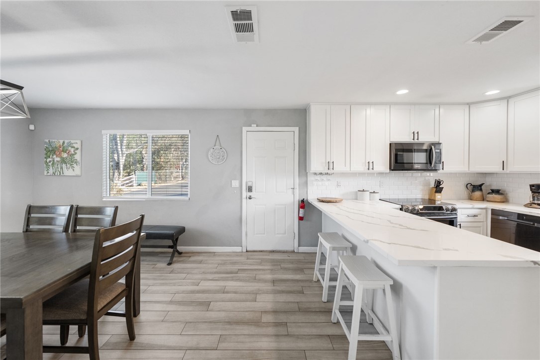35825 Meadow Ridge Road Temecula, CA 92592 - Photo 33 of 75 a kitchen with a stove a sink a microwave a dining table and chairs