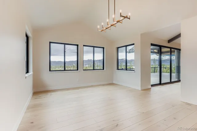 a view of an empty room with wooden floor fireplace and a window