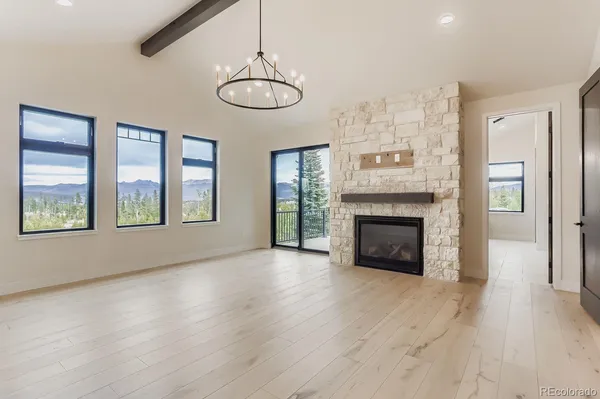 a view of an empty room with wooden floor fireplace and a window