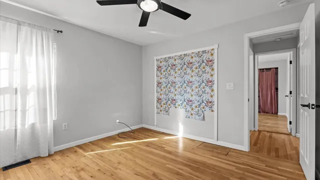 a view of empty room with wooden floor and window