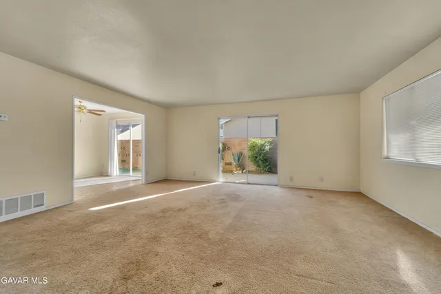 a view of a big room with windows and chandelier fan