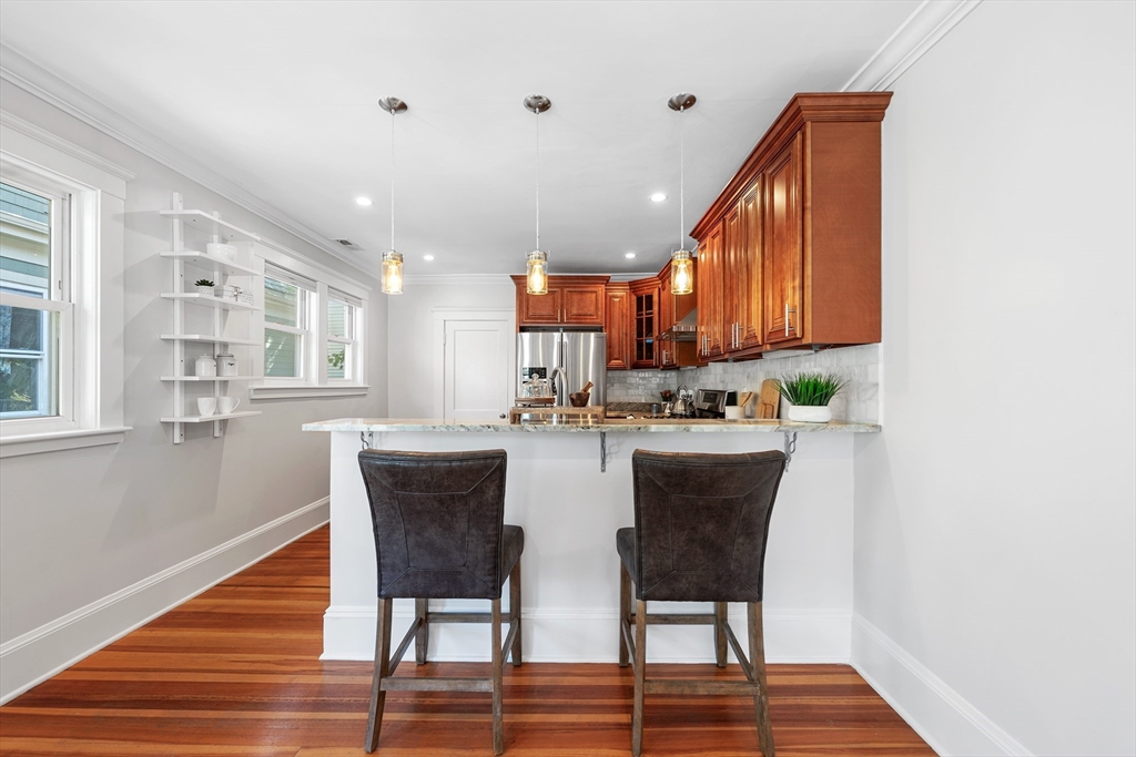 24 Jackson Road, Unit 2 Somerville, MA 02145 - Photo 12 of 35 a kitchen with stainless steel appliances granite countertop a table chairs in it and wooden floor