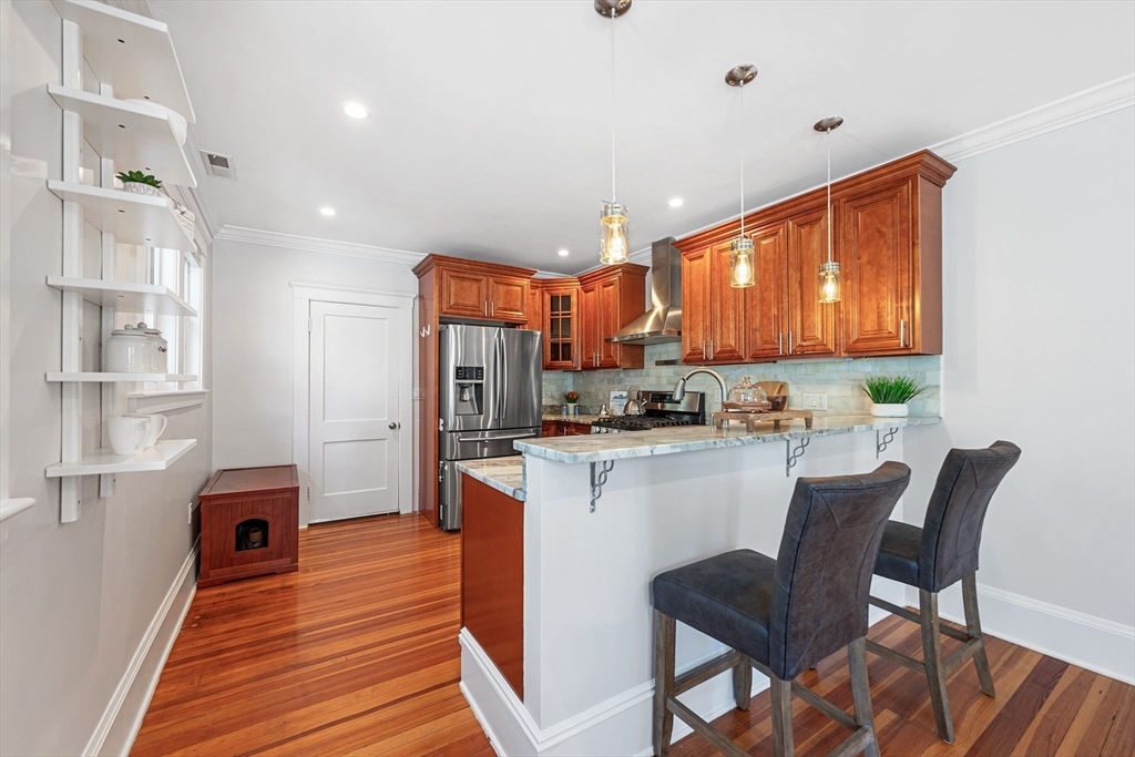 24 Jackson Road, Unit 2 Somerville, MA 02145 - Photo 8 of 35 a kitchen with stainless steel appliances granite countertop a refrigerator a stove top oven a sink with island and chairs