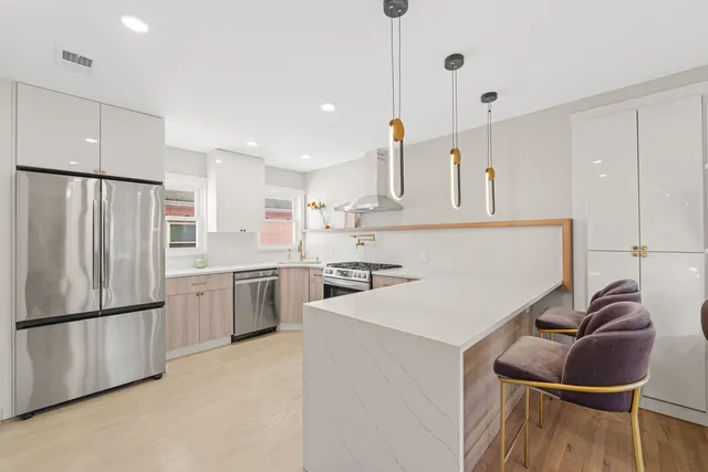 a kitchen with stainless steel appliances granite countertop a sink a stove a refrigerator and island with wooden floor