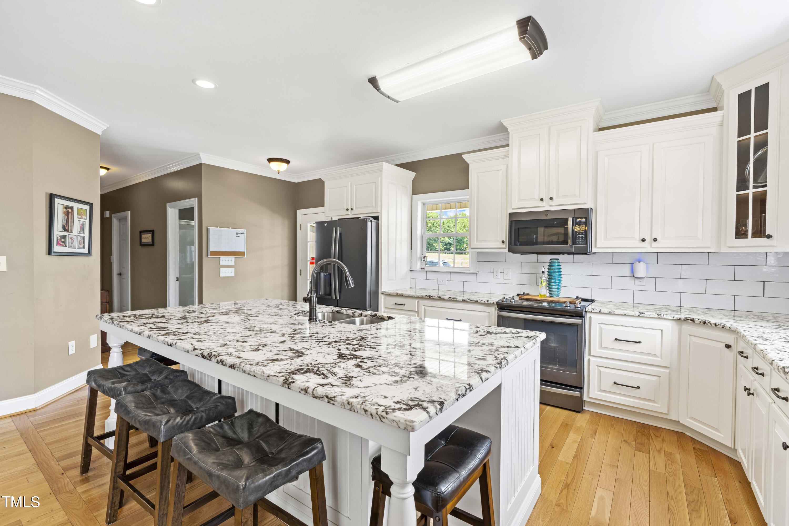 115 Three M Trail Benson, NC 27504 - Photo 19 of 80 a kitchen with stainless steel appliances granite countertop a stove top oven a sink a dining table and chairs with wooden floor
