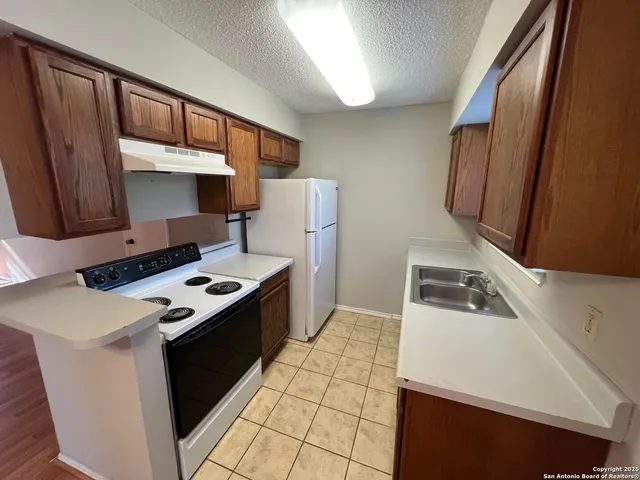 a kitchen that has a sink a stove and a refrigerator