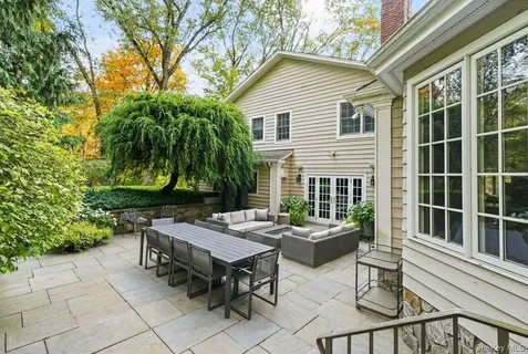 a view of a dinning table and chairs in the patio in front of a house