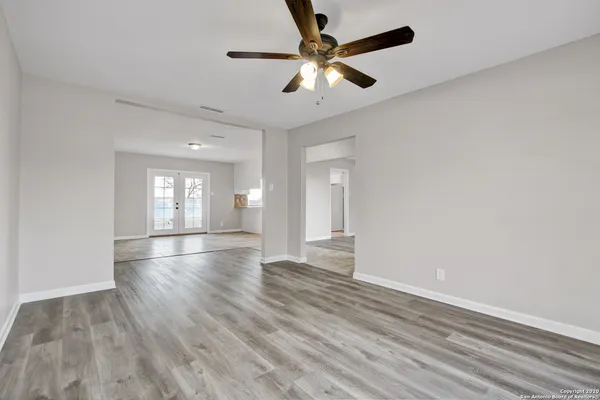 an empty room with wooden floor and windows