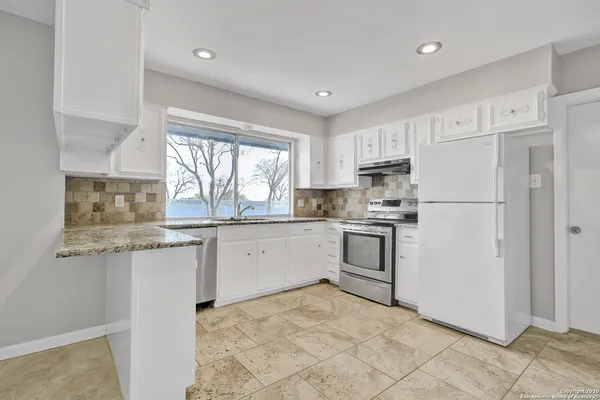 a kitchen with granite countertop white cabinets and white stainless steel appliances