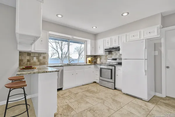 a kitchen with granite countertop white cabinets and white stainless steel appliances