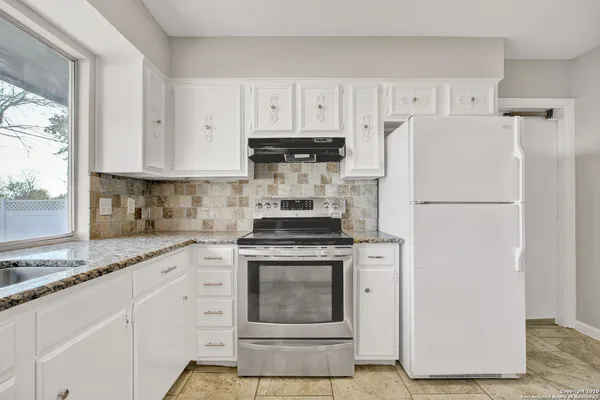 a kitchen with cabinets stainless steel appliances and a window