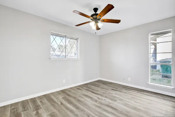 an empty room with wooden floor and windows