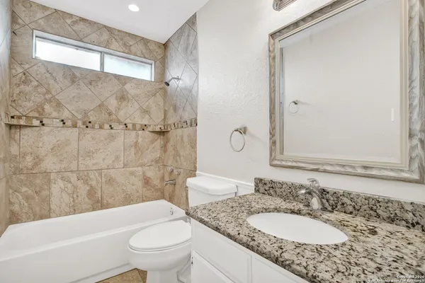 a bathroom with a granite countertop sink a toilet and shower