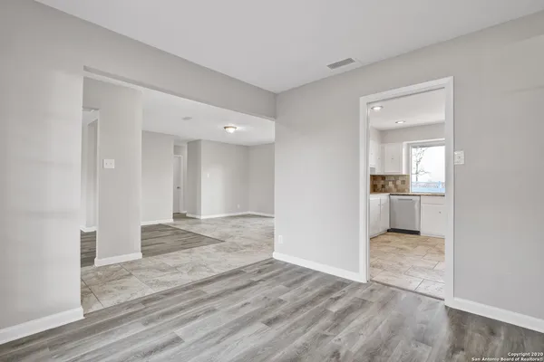 a view of a hallway with wooden floor and a kitchen
