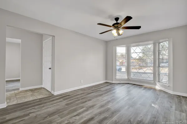 a view of an empty room with a window and wooden floor