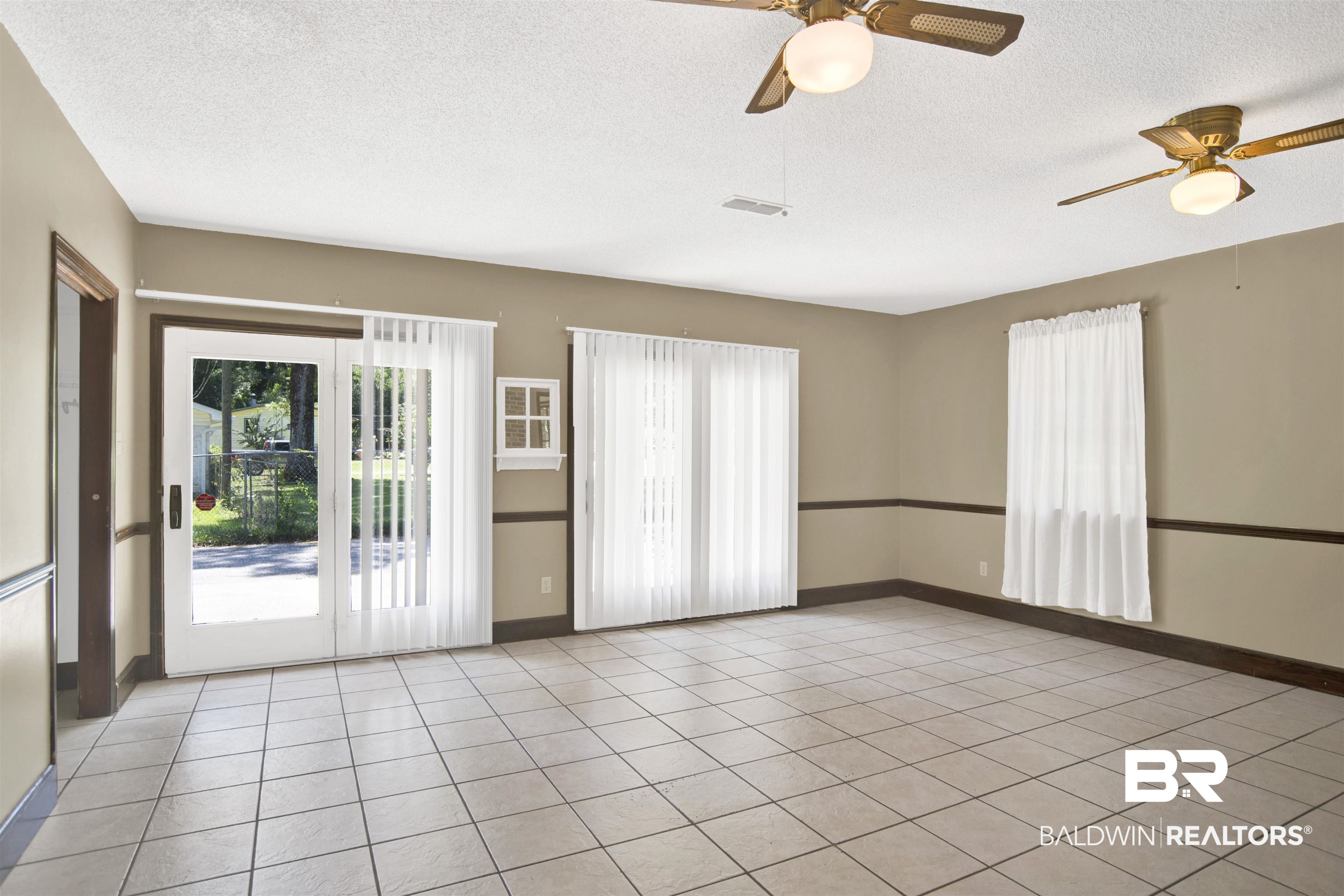 30888 Cemetery Road Daphne, AL 36527 - Photo 16 of 36 Spacious room featuring tile flooring, sliding glass doors to the exterior, multiple windows, and two ceiling fans with integrated lighting