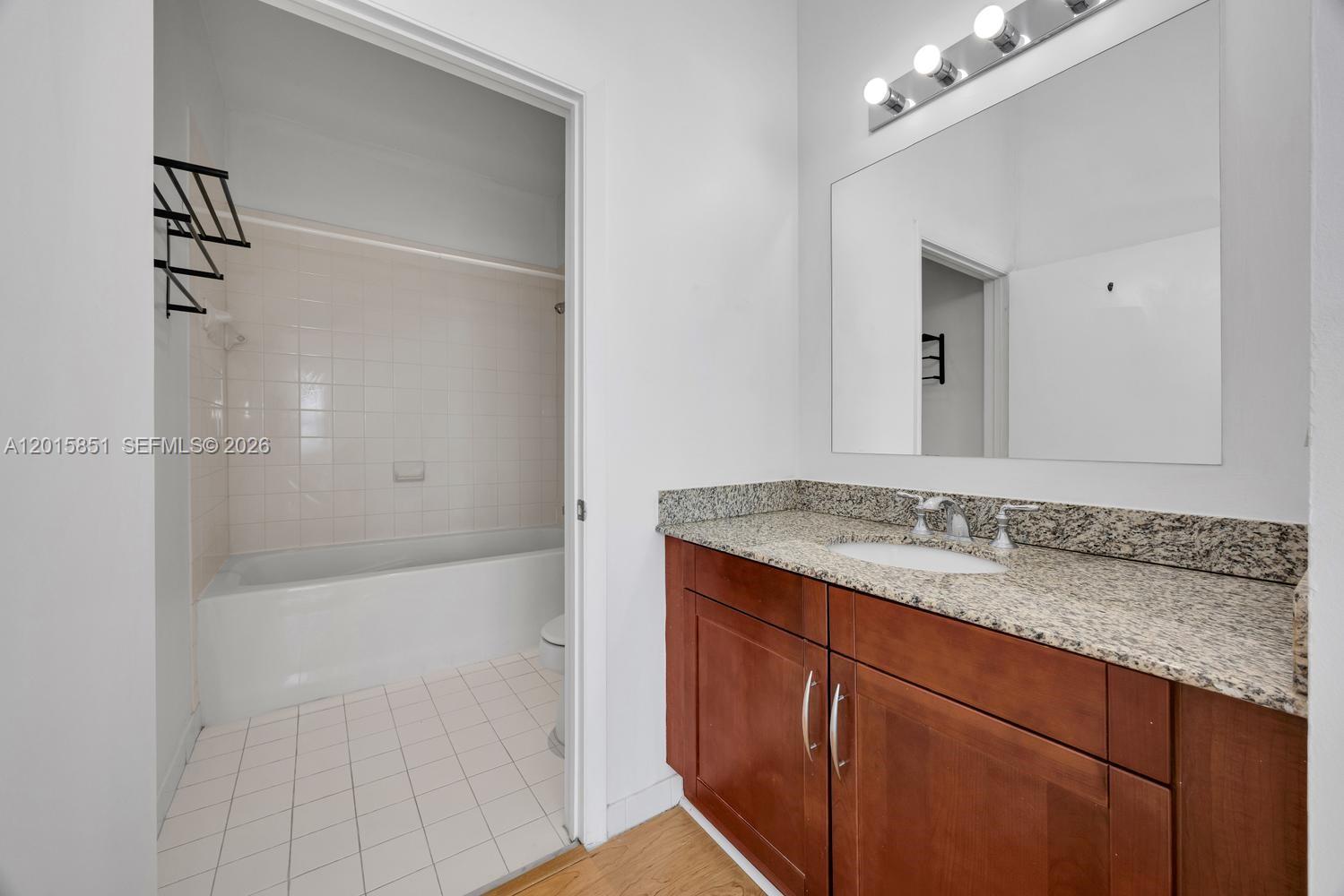 7275 Southwest 90th Street, Unit C719 Miami, FL 33156 - Photo 14 of 25 a bathroom with a granite countertop sink and a mirror