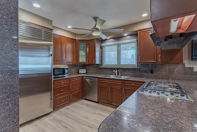 a kitchen with stainless steel appliances granite countertop a sink a stove and a refrigerator