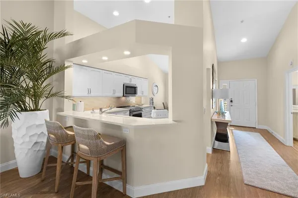 a kitchen with stainless steel appliances kitchen island a table chairs sink and cabinets