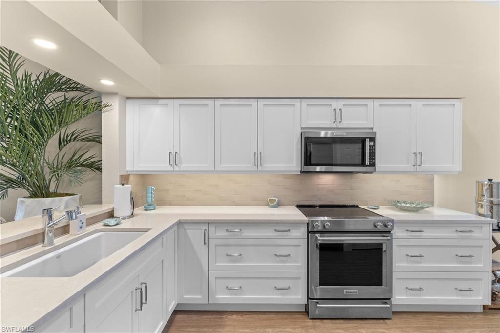 2215 Chesterbrook Court, Unit 2 Naples, FL 34109 - Photo 9 of 38 a kitchen with stainless steel appliances granite countertop a sink dishwasher a stove and a microwave oven with white cabinets