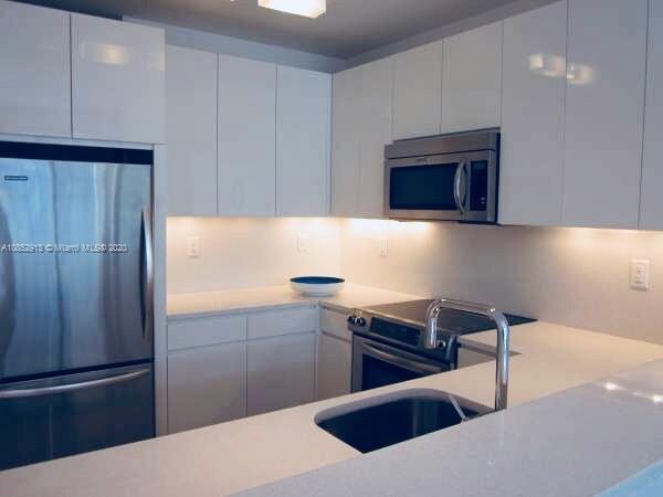 200 23rd Street, Unit 203 Miami Beach, FL 33139 - Photo 16 of 79 a kitchen with stainless steel appliances kitchen island granite countertop a refrigerator a sink and a stove