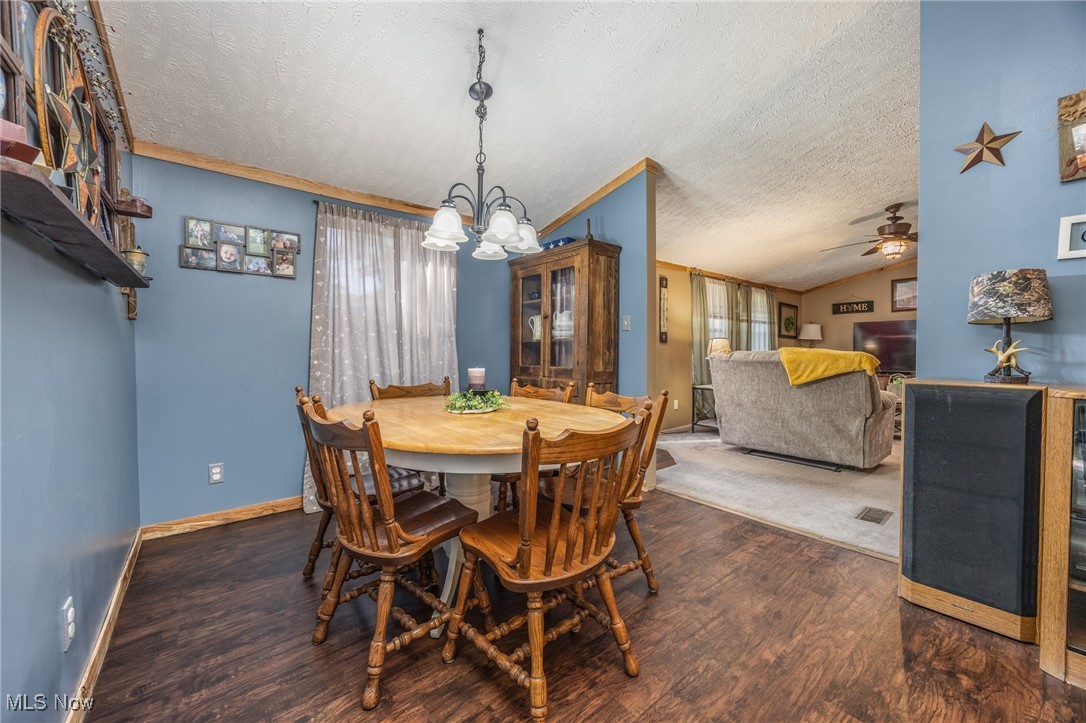 1788 Rosenbush Road Newport, OH 45768 - Photo 14 of 34 Dining area with a textured ceiling, dark wood-type flooring, vaulted ceiling, ornamental molding, and a chandelier