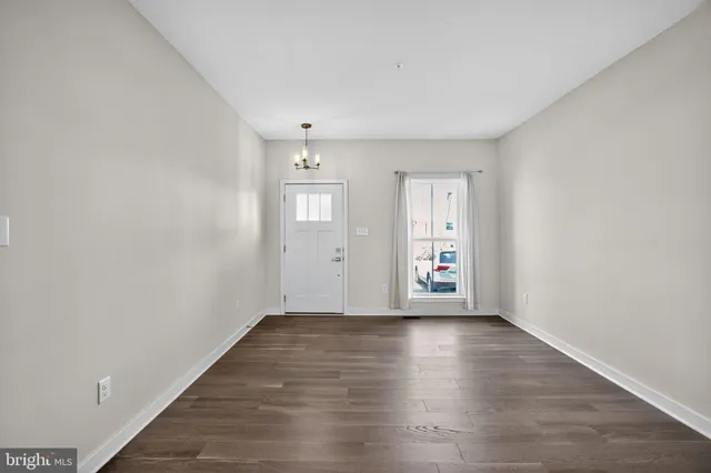 a view of an empty room with window and wooden floor
