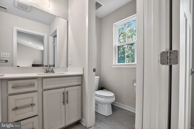 a bathroom with a granite countertop toilet a sink and a mirror