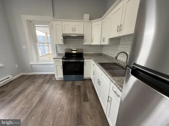 a kitchen with granite countertop a sink wooden floor and stainless steel appliances