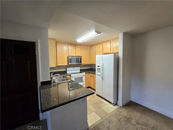 a kitchen with granite countertop stainless steel appliances a refrigerator microwave and sink