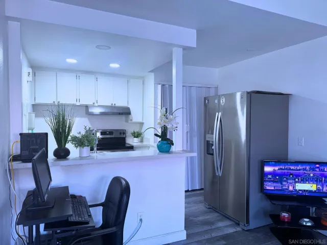 a kitchen with stainless steel appliances granite countertop a refrigerator a stove a sink a dining table and chairs with wooden floor